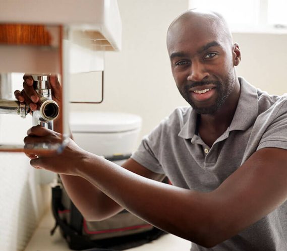 male plumber working on sink happy after getting great plumber digital marketing